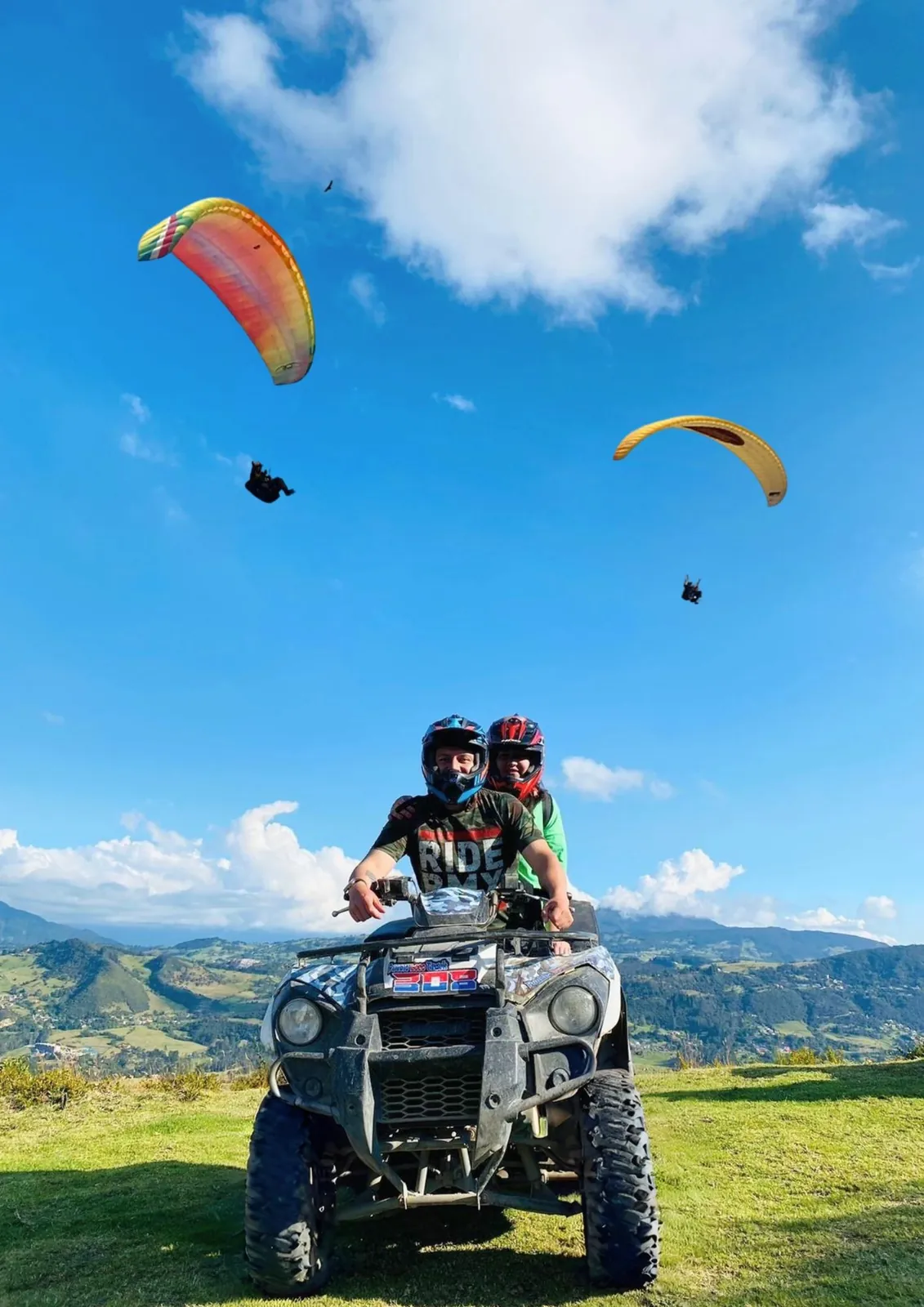Pareja en cuatrimoto con parapentes volando sobre La Calera